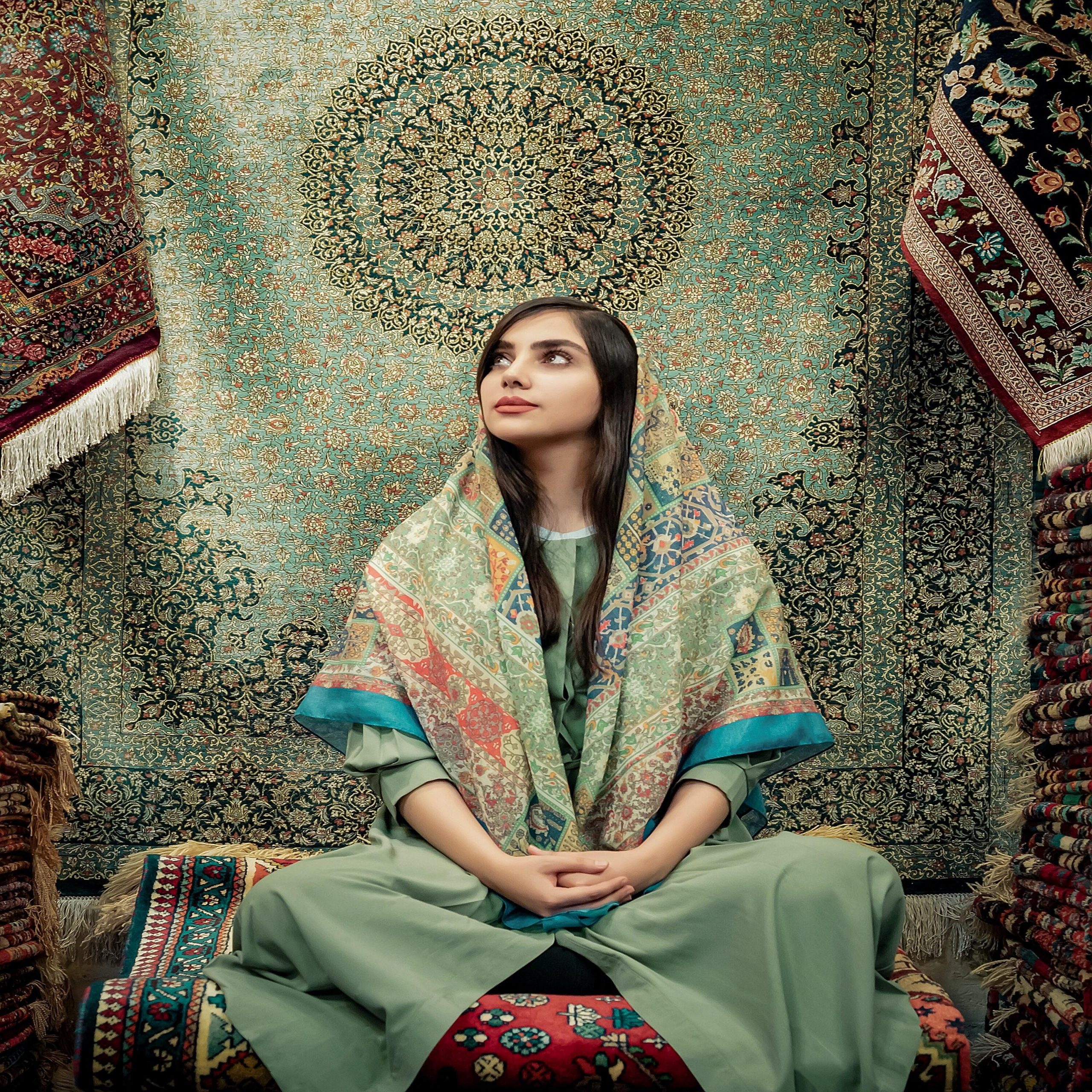 an iranian girl sit on a carpet